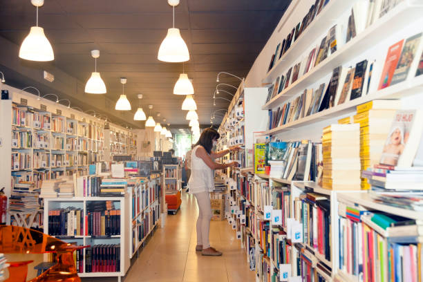 istock Woman organizing the shelf in the bookstore with protector 1253294380
