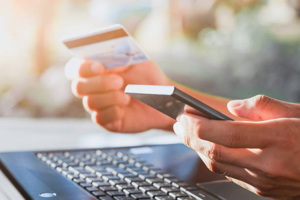 istock Man using smartphone and laptop computer for online shopping at home, Hand holding mobile phone with payment Detail page display and credit card, online 1253297756