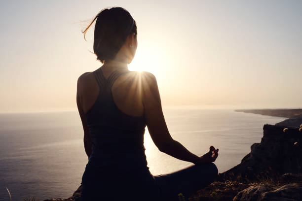 istock Young woman practicing yoga over sunset sea 1253299141