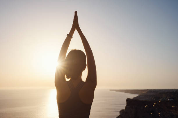 istock Young woman practicing yoga over sunset sea 1253299315