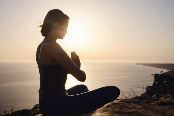 istock Young woman practicing yoga over sunset sea 1253299331