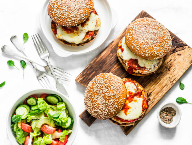 panino integrale fatto in casa, pollo alla griglia, salsa di pomodoro, hamburger di mozzarella sul tagliere e pomodoro, cetriolo, insalata di avocado su sfondo leggero, vista dall'alto. laici piatti - mozzarella tomato sandwich picnic foto e immagini stock