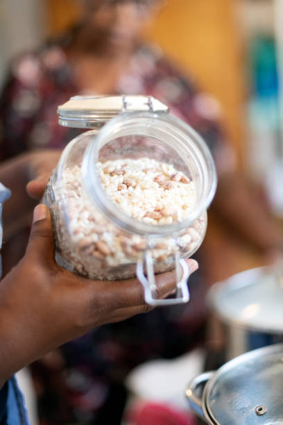 Hands hold open glass jar of dried beans and maize