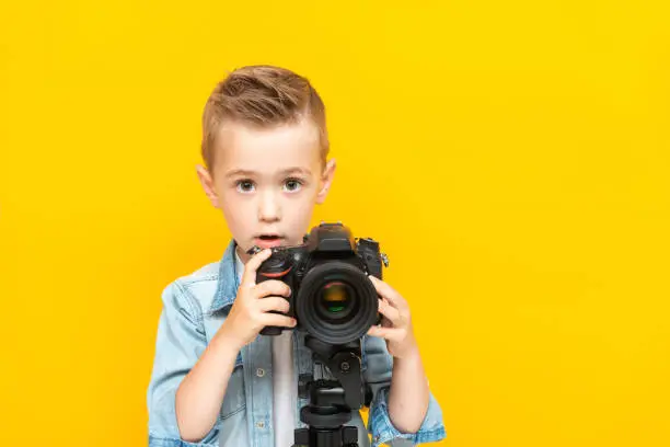 Adorable boy taking a photo using a digital camera on a tripod.