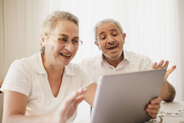 istock Happy senior couple wave having video call on tablet talking with relatives, smiling aged husband and wife sit on chair at home communicating via online using computer. Elderly and technology concept 1253303293