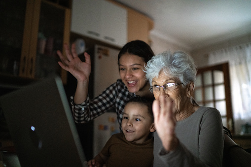 Grandmother and grandchildren waving on a video call at home