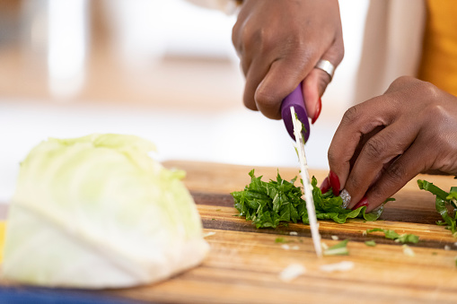 Close up woman chopping fresh spinach on kitchen counter