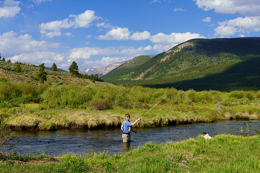 Flyfisherman fly fisherman fishing on river with Tetons in Background