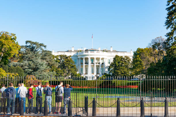 大統領またはアメリカの故郷であるホワイトハウスを見てフェンスで外に立っている学校の生徒のグループ - editorial building exterior built structure travel destinations ストックフォトと画像