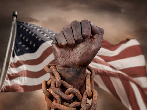 main foncée dans des chaînes avec le drapeau américain derrière - esclavage photos et images de collection