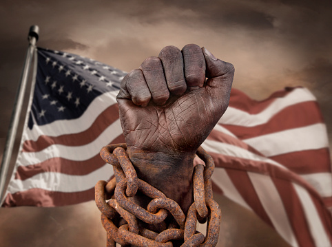 Dark hand in chains with US flag behind