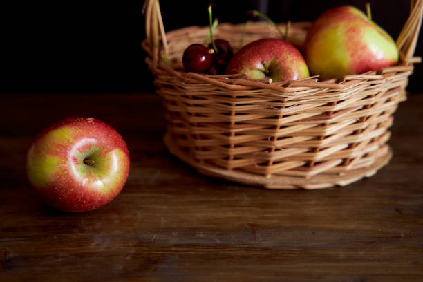 istock Braided basket with red apples on a black background 1253306719