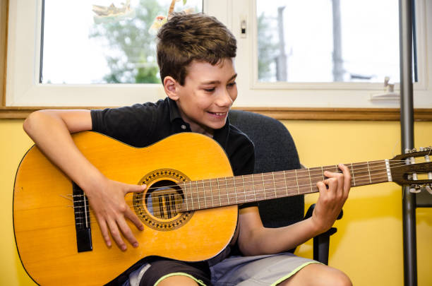 istock Teenage boy playing guitar 1253306790