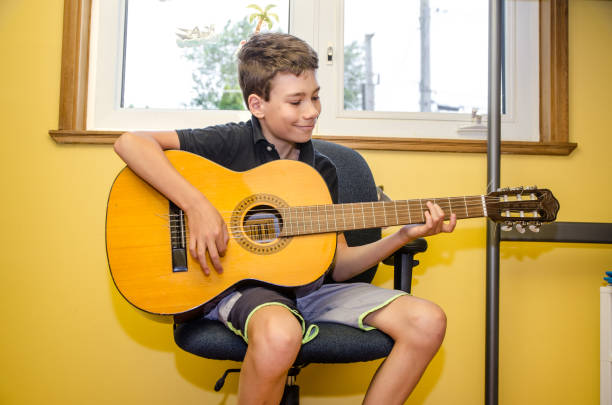 istock Teenage boy playing guitar 1253306819