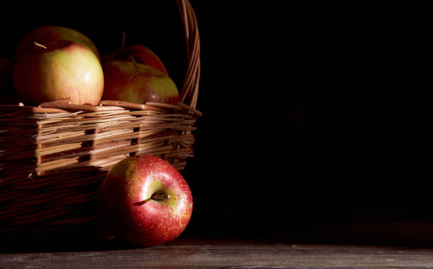 istock Braided basket with red apples on a black background 1253307156