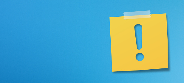 Yellow sticky note paper with exclamation mark on blue background