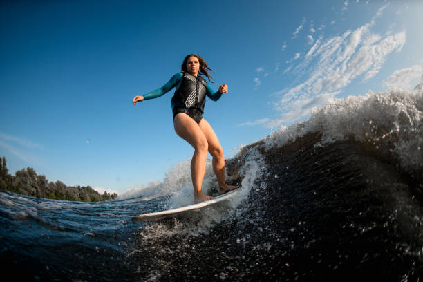 istock Young brown-haired woman on board riding wave 1253310183
