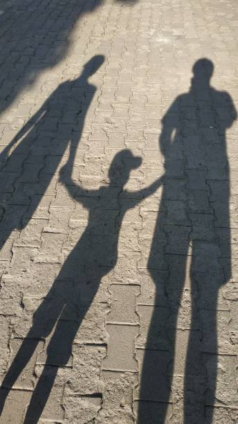 istock young family holding son's hands, shadows from the sun 1253310356