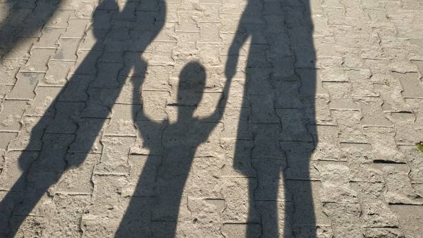 istock young family holding son's hands, shadows from the sun 1253310367