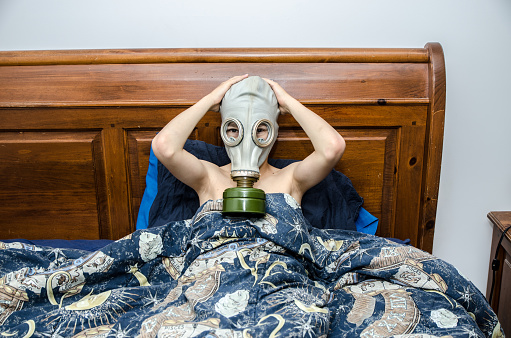 Boy in bed with gas mask with hands on head