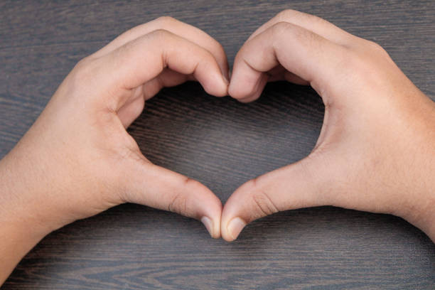 istock Hand shoot, a hand create a shape of heart on wooden table 1253311217