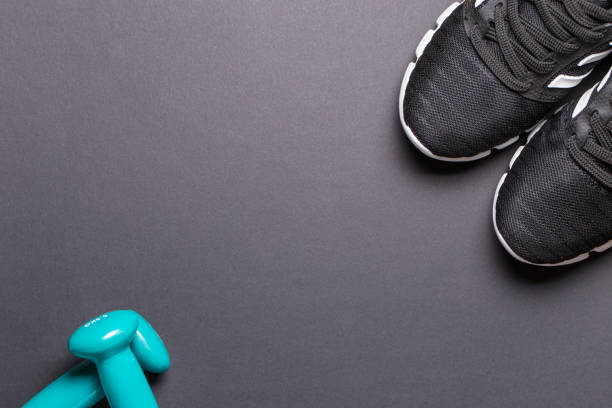 istock Black sneakers and turquoise dumbbells with a white sole on a black background 1253313440