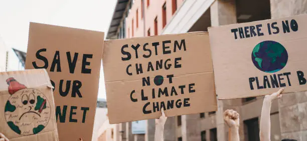 Group of people participating in a protest against global warming. Climate change protest concept. They are holding banner signs.