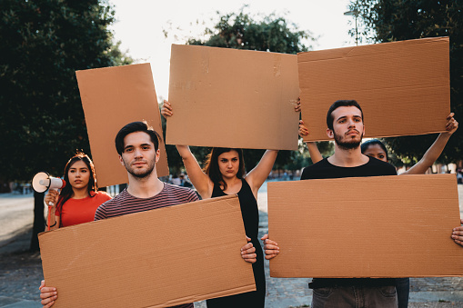 Group of people holding banner signs during a social protest - Empty signs for copy space. Hispanic and caucasian ethnicities.