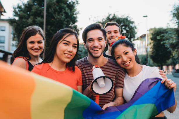 Five friends together at an LGBTQI Pride event Five friends together at an LGBTQI Pride event. Hispanic and caucasian ethnicities. They are looking at camera and smiling. lgbtqia pride event photos stock pictures, royalty-free photos & images