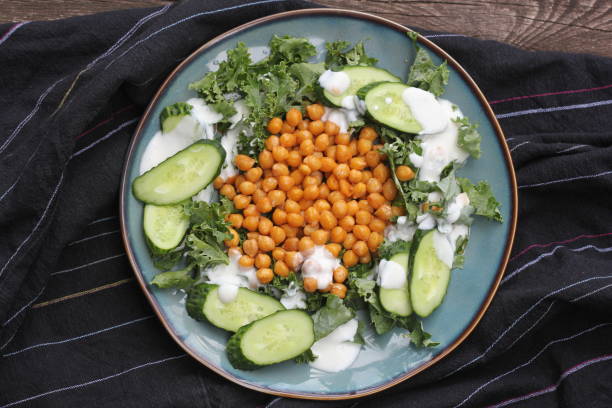 Photo of Healthy vegetarian salad with roasted chickpeas,kale, cucumber and dressing. Healthy detox eating. Vegan and vegetarian food.