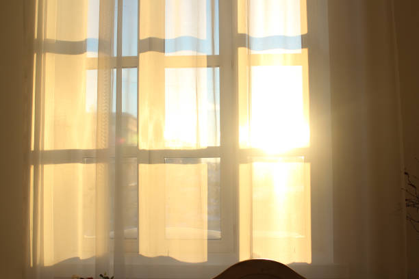 istock Window silhouette on the curtains. Rays of sunshine through a white curtain. 1253316969