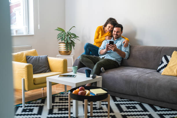 istock Happy couple using mobile phone at home stock photo 1253318122