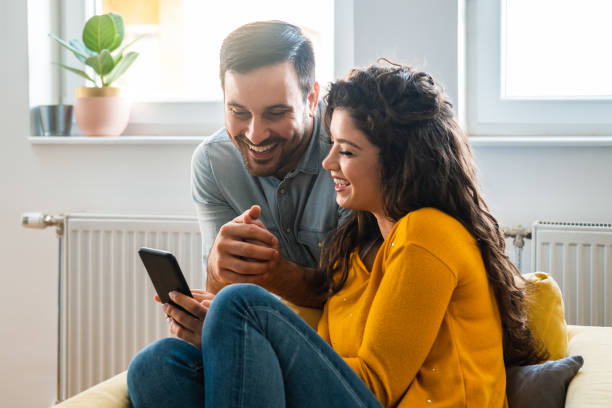Couple using mobile phone at home stock photo