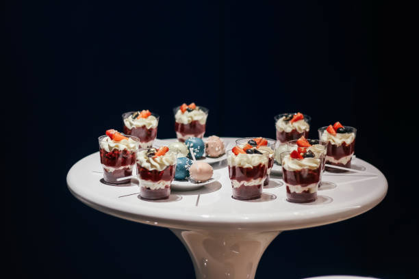 Desserts with whipped cream and strawberries on a white table. Glamorous style