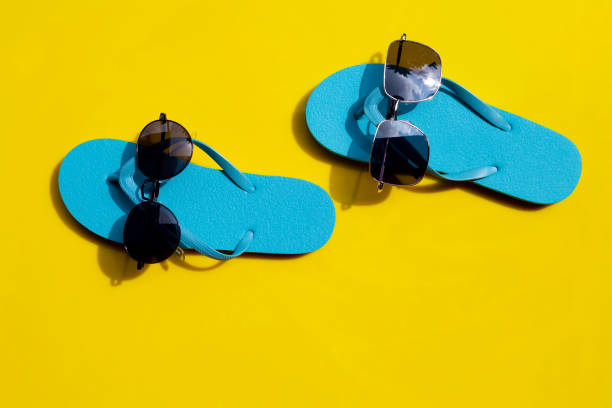 istock Blue flip flops with sunglasses on yellow background. Enjoy summer 1253320262
