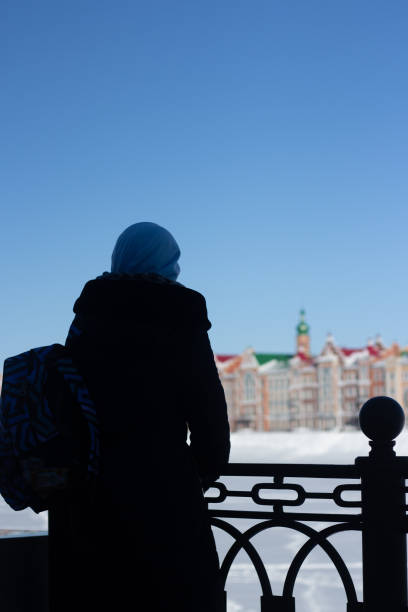 casas frente al mar en la ciudad de yoshkar-ola, en rusia. nieve de invierno. vistas de la ciudad de yoshkar-ola. casas coloridas. viajero musulmán con una mochila mira a la ciudad - people personal accessory town hat fotografías e imágenes de stock