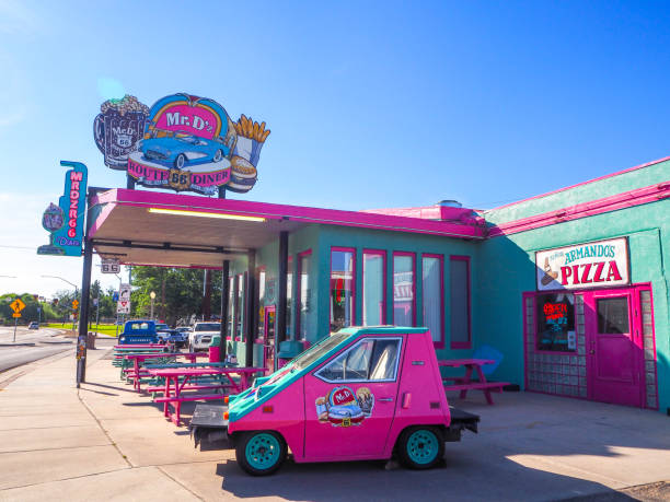 Tow girls drinking milkshakes in a classic diner with their friends.