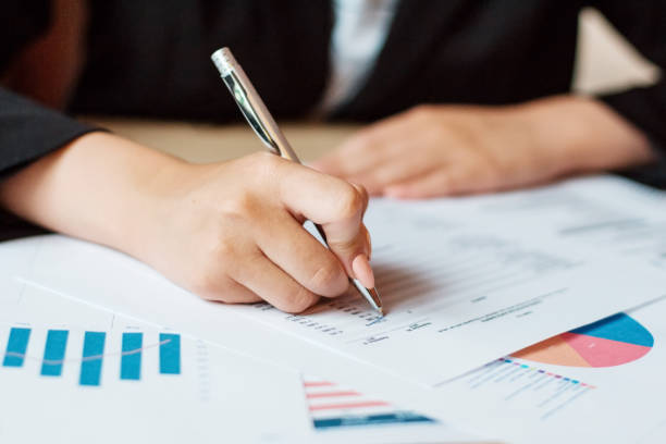 istock Hand of business woman pointing document data graph and chart with pen, marketing and investment, report of statistics profit for financial, economic and growth of finance, management and planning. 1253323091