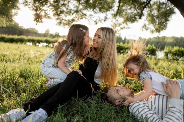 istock Unity of a happy parents with their daughters resting on a green 1253323208