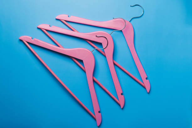 istock Pink empty wooden clothes hangers on pastel blue background 1253324523