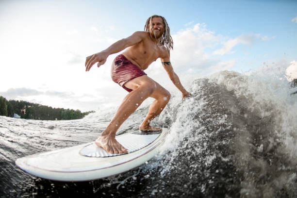 istock close-up of cheerful athletic young man on board riding wave 1253324642