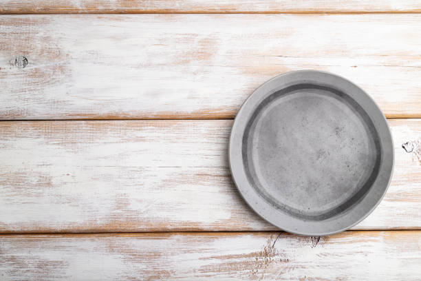 istock Empty gray ceramic plate on white wooden background. Top view, copy space, flat lay. 1253326975