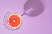 Grapefruit cocktail slice top view on purple background