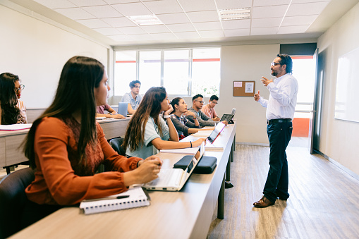 Teacher giving advice to diverse University Students in Classroom