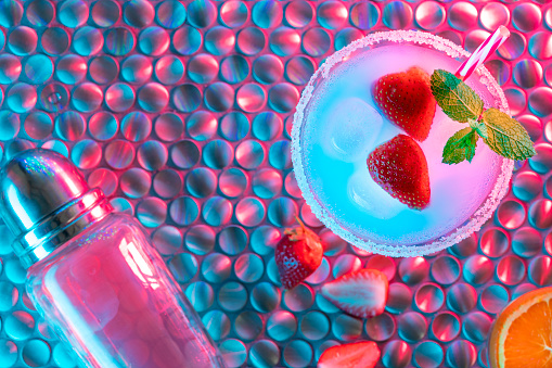 Strawberry cocktail mojito in glowing lights disco psychodelic background on psychedelic metal table