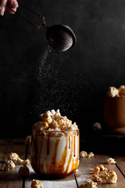 istock Milkshake with popcorn and caramel syrup on a black background. Sprinkle with powdered sugar. 1253328384