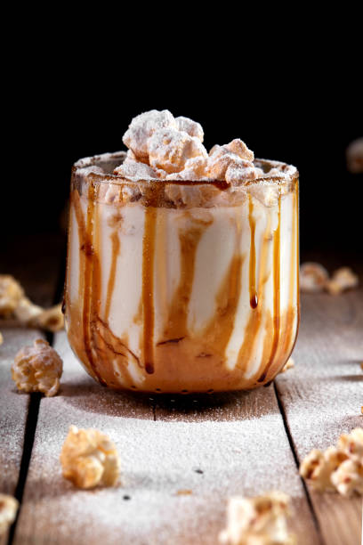 istock Milkshake with popcorn and caramel syrup on a black background. Sprinkle with powdered sugar. 1253328386
