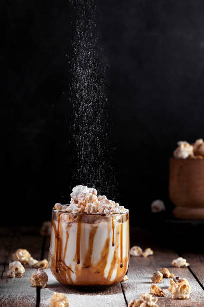 istock Milkshake with popcorn and caramel syrup on a black background. Sprinkle with powdered sugar. 1253328388