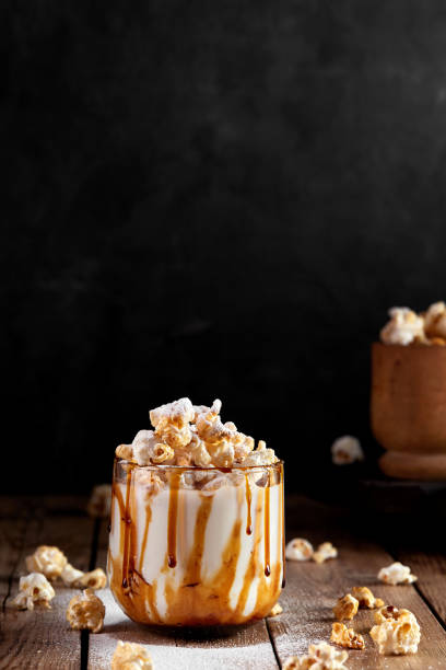 Milkshake with popcorn and caramel syrup on a black background. Sprinkle with powdered sugar.