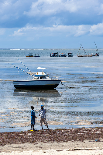 Mombasa, Kenya - October 04, 2012: Fishermen at Mombasa Coast. There is less water due to the tide time on the shore and fishermen are waiting for the waters to return to the shore